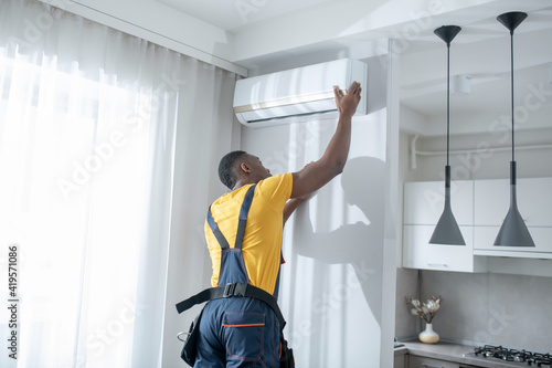 Service man in yellow tshirt looking busy while installing the air-conditioner