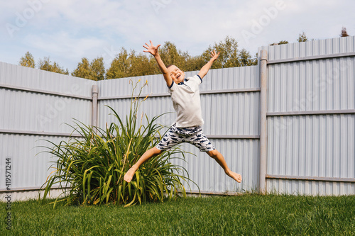 Little happy boy jumping in backyard.