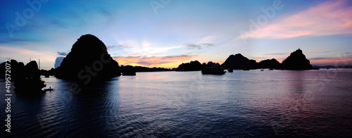 Beautiful sunset Tourist junks floating among limestone rocks at HaLong Bay, South China Sea, Vietnam, Southeast Asia.