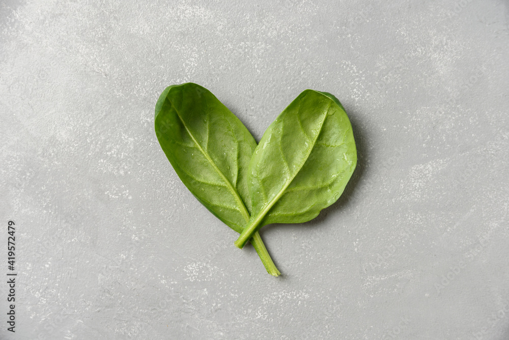 Naklejka Spinach leaves in heart shape on grey concrete background
