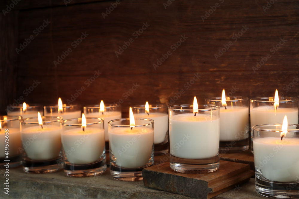 the burning luxury aromatic scented candle glass on the wooden table with background of vintage wooden wall of the cottage in the living room to creat relax ambient during christmas party celebration the burning luxury aromatic scented candle glass on the wooden table with background of vintage wooden wall of the cottage in the living room to creat relax ambient during christmas party celebration