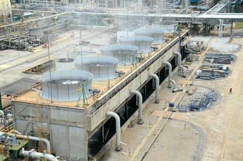 Cooling tower and cooling fan blowing steam on the air in chemical plant, refinery plant, oil and gas plant during operation.