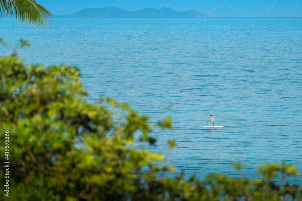 Woman stand up paddle boarding across the sea at Panwa Beach, Phuket, Thailand