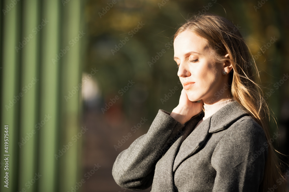 Portrait of a beautiful young woman in a gray coat. The attractive woman closed her eyes dreamily. Delicate and melancholic autumn mood. Fall season. Shallow depth of field and blurred background. Portrait of a beautiful young woman in a gray coat. The attractive woman closed her eyes dreamily. Delicate and melancholic autumn mood. Fall season. Shallow depth of field and blurred background.