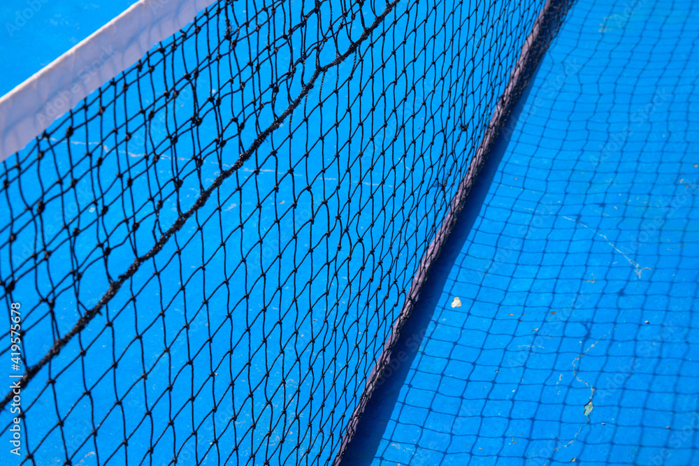 Blue tennis court with black net. Empty sport field photo. Hard court cover for lawn tennis. Summer sport activity outdoor. White markup on blue court. Sunny day on tennis court. Sport field in park Blue tennis court with black net. Empty sport field photo. Hard court cover for lawn tennis. Summer sport activity outdoor. White markup on blue court. Sunny day on tennis court. Sport field in park