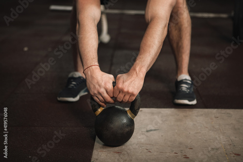 Unrecognizable male athlete working out with kettlebell