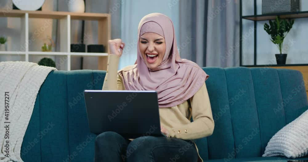 Attractive satisfied smiling young arabic woman in hijab sitting on the ...