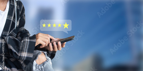 Customer pressing on smartphone with five star icon for feedback review satisfaction service and blurred space office  background, feedback review concept