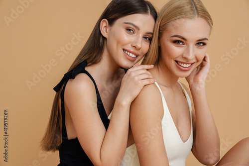 Happy two women wearing swimsuits hugging and smiling at camera