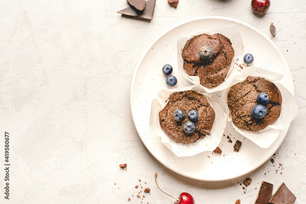 Homemade fresh chocolate muffins with berries and chocolate pieces. Top view. Homemade fresh chocolate muffins with berries and chocolate pieces. Top view.