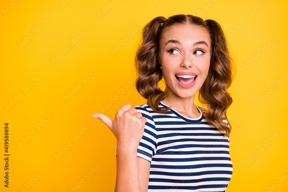 Photo of pretty impressed young lady dressed striped outfit pointing thumb up looking empty space isolated yellow color background Photo of pretty impressed young lady dressed striped outfit pointing thumb up looking empty space isolated yellow color background