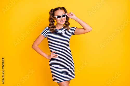 Portrait of attractive thin cheerful girl wearing touching specs posing isolated on bright yellow color background