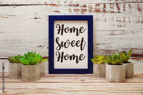 Blue Photo Frame with Home Sweet Home written and small cactus decoration on wooden background