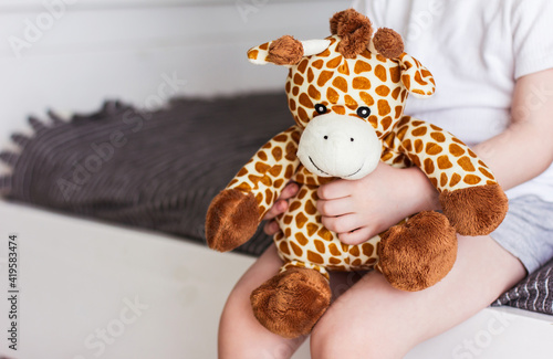 Canvas Print Child  holding a giraffe plush toy on a gray background