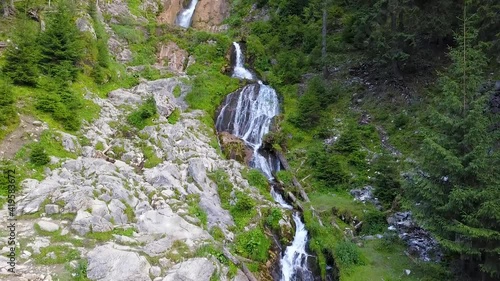 Ascending along Cascada Cailor waterfall, located in Rodna Mountains. The huge cascade forms numerous steps over which the mountain stream flows rapidly, along mossy rocks and spruce trees. Romania. photo