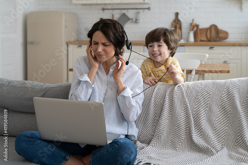 фотографія Nervous freelancer mother sitting on couch at home office during lockdown, working on laptop