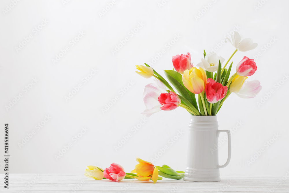 beautiful   tulips in white jug on white background