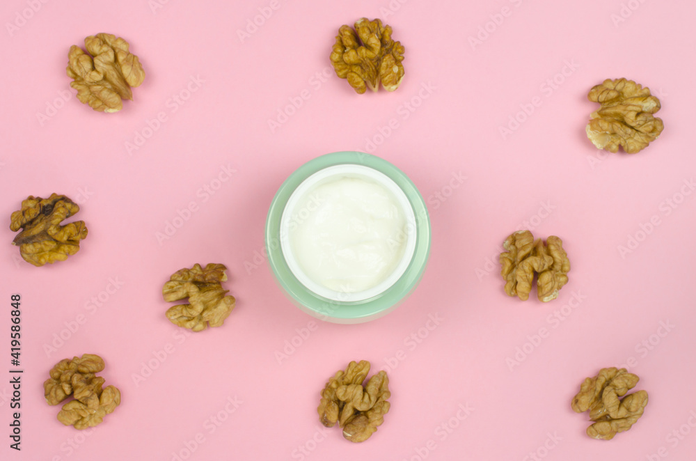 open jar of cream and walnuts on a pink background. Organic cosmetics for skin care. Mock-up bottle for branding and label open jar of cream and walnuts on a pink background. Organic cosmetics for skin care. Mock-up bottle for branding and label