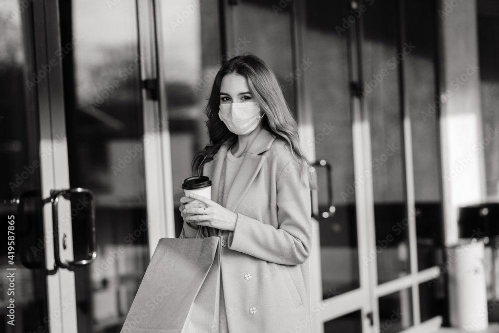 Young female wearing a mask for prevent virus with shopping bags on narrow street in Europe. Young female wearing a mask for prevent virus with shopping bags on narrow street in Europe.