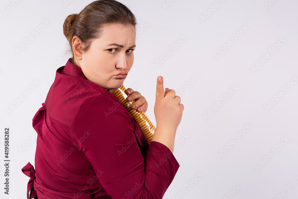 An offended chubby caucasian woman hides a pack of cookies in her hands and shows her finger no. Not desire is shared. Addiction to sweets. Obesity. An offended chubby caucasian woman hides a pack of cookies in her hands and shows her finger no. Not desire is shared. Addiction to sweets. Obesity.