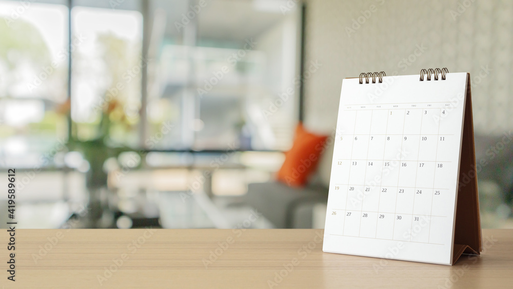 white paper desk calendar on wood table with blurred bokeh background appointment and business meeting concept white paper desk calendar on wood table with blurred bokeh background appointment and business meeting concept