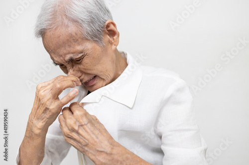 Elderly was sniffing her clothes smell musty or shirt smell moldy,bad smell,foul odor from washing,unclean laundry,senior woman is smelling stinky,scent detergent,pungent fragrance of fabric softener photo