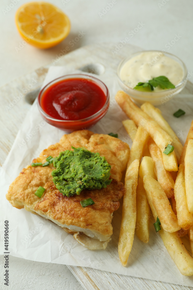 Concept of tasty eating with fried fish and chips on white textured table Concept of tasty eating with fried fish and chips on white textured table