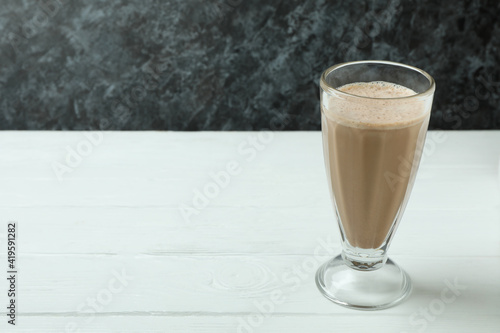 Glass of chocolate milkshake on white wooden table