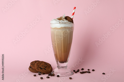 Glass of milkshake, coffee seeds and cookies on pink background