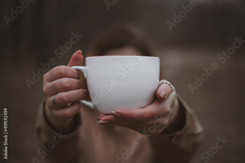 White cup mockup. A girl in the woods holding a white mug in her hands