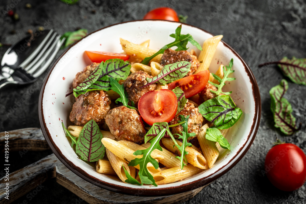 penne pasta with meatballs and tomato sauce on dark background. banner, menu recipe, top view penne pasta with meatballs and tomato sauce on dark background. banner, menu recipe, top view