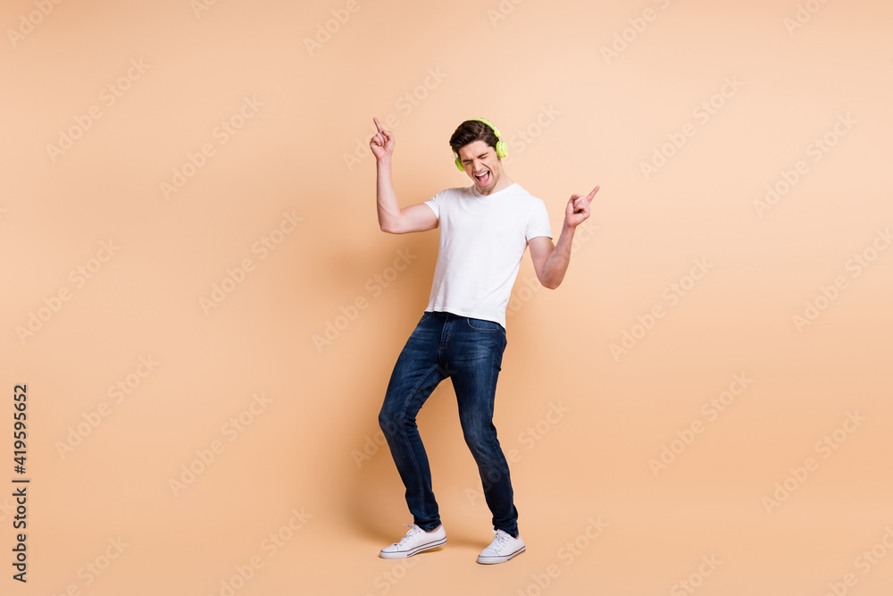 Full size photo of carefree guy closed eyes direct fingers up open mouth isolate don beige color background Full size photo of carefree guy closed eyes direct fingers up open mouth isolate don beige color background
