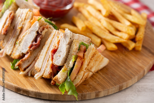 Club sandwich and French fries with ketchup sauce on wooden table photo