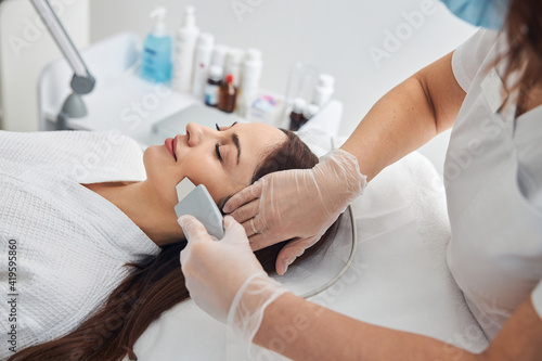 Beautiful woman receiving facial treatment in cosmetology clinic