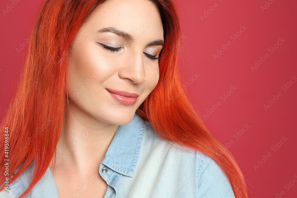 Young woman with bright dyed long hair on red background, closeup