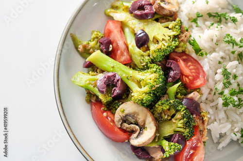 Oven vegetables of broccoli, mushrooms, tomatoes and olives with rice and parsley garnish, healthy cooking with fresh ingredients, close up from above, selected focus