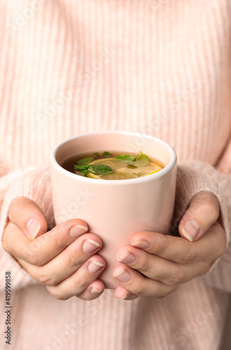 Woman holding cup with hot tea, closeup