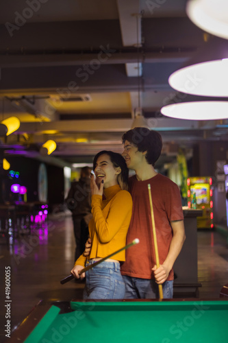 Smiling Young couple spending time in billiard room.