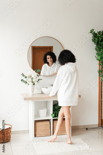 Woman with curly hair with bare legs looks in a round mirror