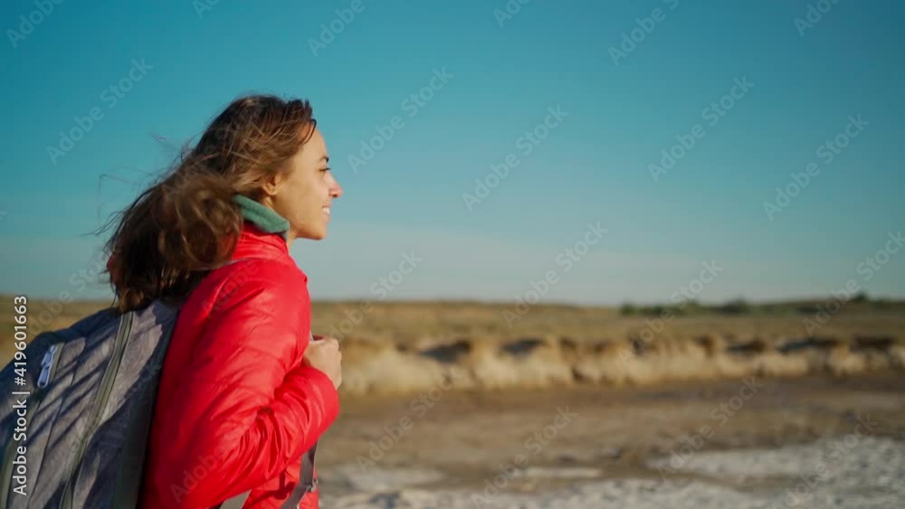 slow motion portrait of happy confident and joyful young woman hiker in red jacket walking on salty lake coast with clay shore slow motion portrait of happy confident and joyful young woman hiker in red jacket walking on salty lake coast with clay shore