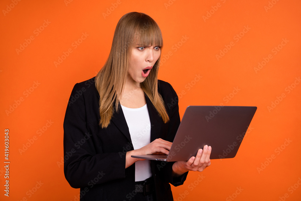 Portrait of pretty worried outraged girl expert using laptop reading report isolated over bright orange color background Portrait of pretty worried outraged girl expert using laptop reading report isolated over bright orange color background