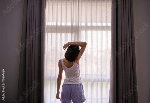 Young Asian woman stretching in bed after wake up, back view