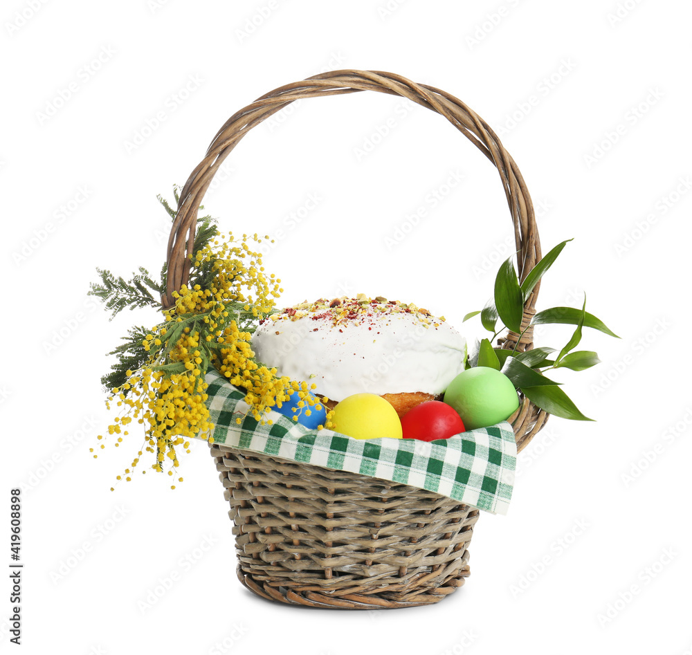 Fototapeta premium Basket with delicious Easter cake, dyed eggs and flowers on white background