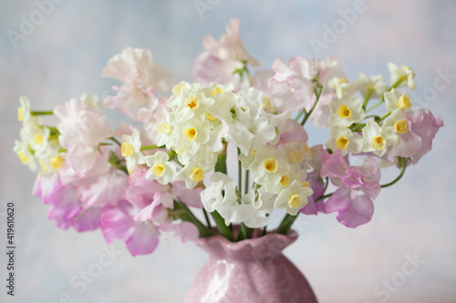 Bouquet in a vase of sweet pea flowers and daffodils on a decorative colored background. Close-up  blur  selective focus.