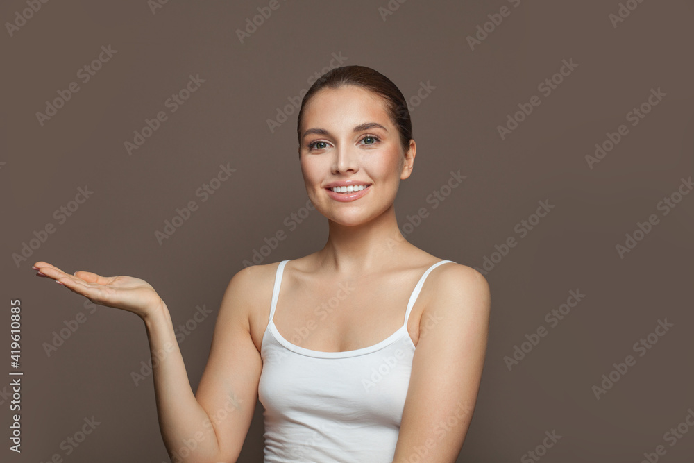Healthy woman with clear skin smiling and showing empty open hand on brown background Healthy woman with clear skin smiling and showing empty open hand on brown background