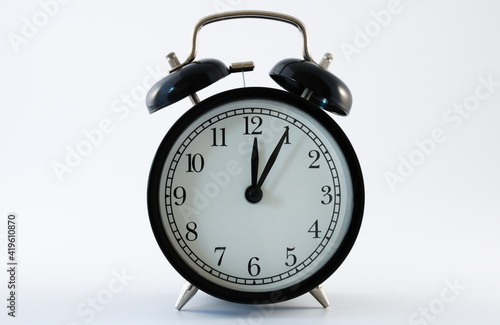 Retro alarm clock showing 5 minutes past 12, isolated on white background