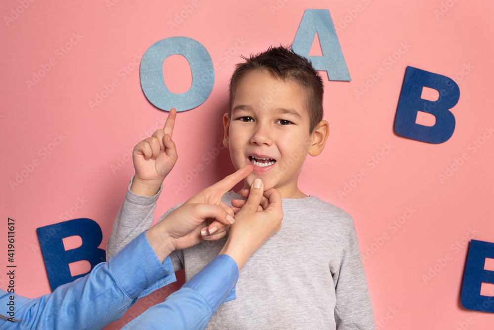 Portrait of a 4 year old boy speech therapy concept on pink background. Correct pronunciation