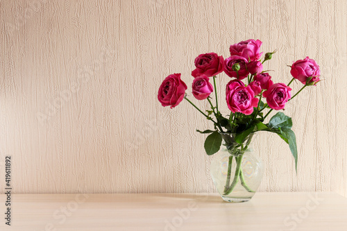 Beautiful tender pink roses in glass vase on the table with copy space. Minimal home decor. Festive floral backround