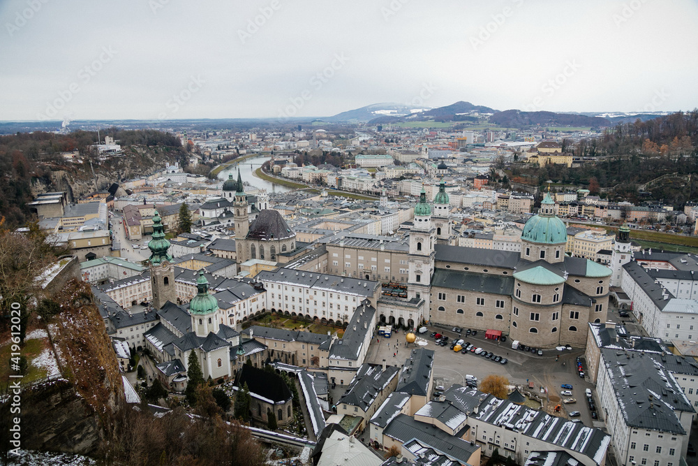 Fototapeta premium Panoramic top scenery of old town, viewpoint at Hohensalzburg Fortress, during cloudy and gloomy winter day, Saint Peter's Abbey and baroque Salzburg Cathedral, Salzburg, Austria