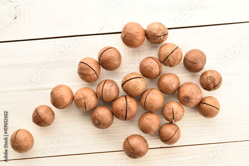 Several ripe brown macadamia nuts, close-up, on a wooden table.